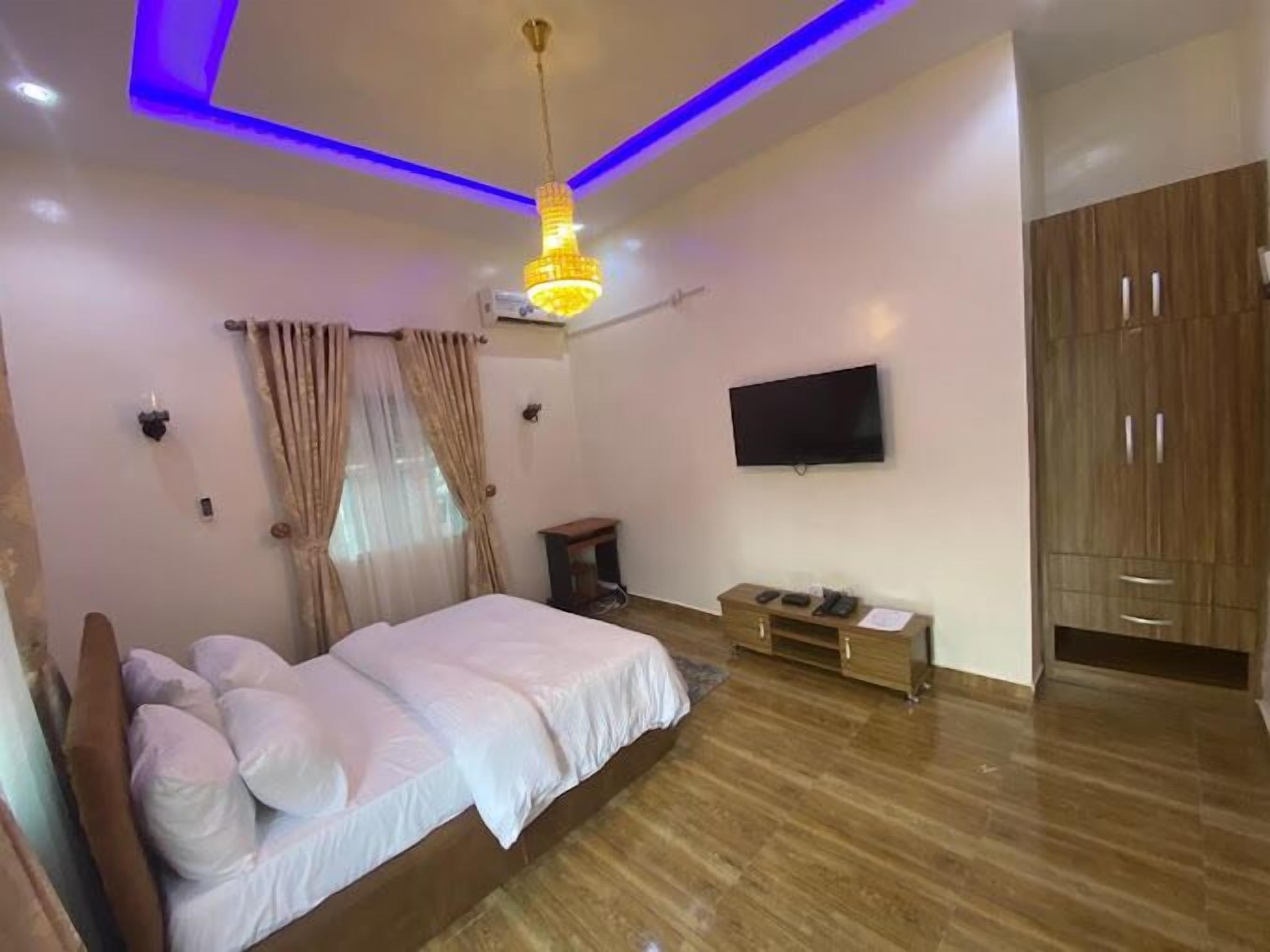 A bedroom with a bed, a TV, a wardrobe, and a ceiling light.