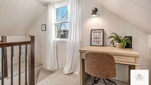 A room with a wooden desk, a chair, a window with white curtains, and a potted plant. - The Harlan City Cottage - Extended Stay Welcome (Grand Rapids)