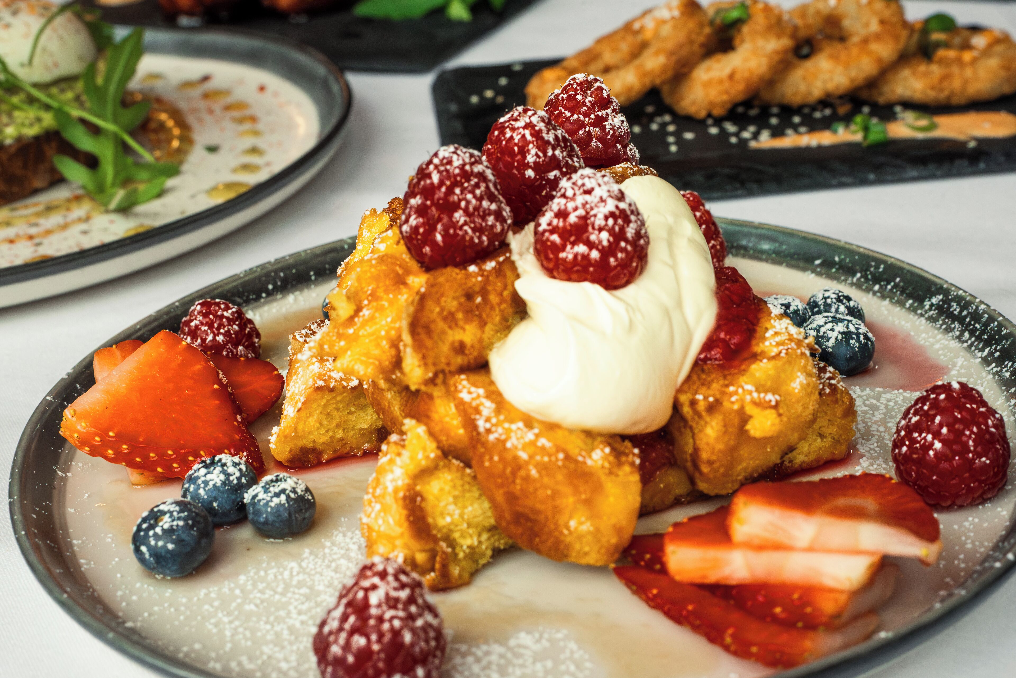 A plate of French toast with berries and powdered sugar.