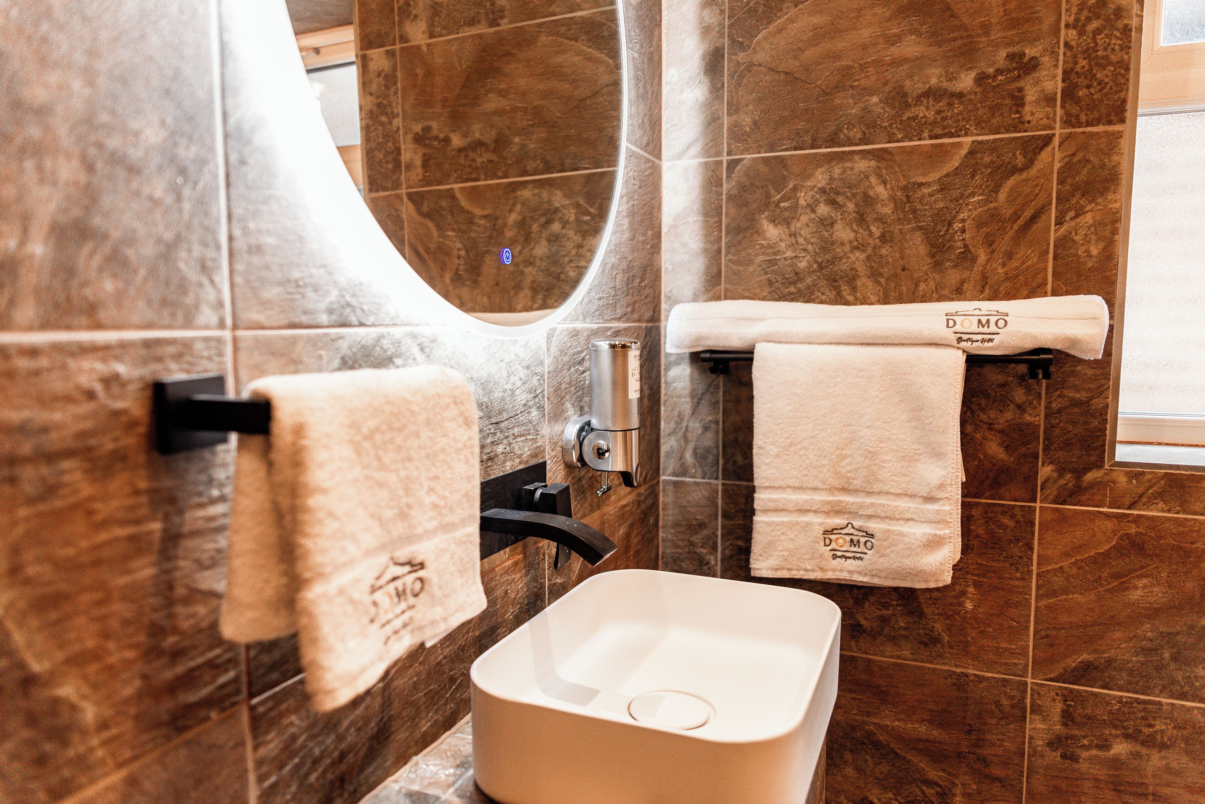 A bathroom with a rectangular sink, two towels hanging on hooks, and a mirror.