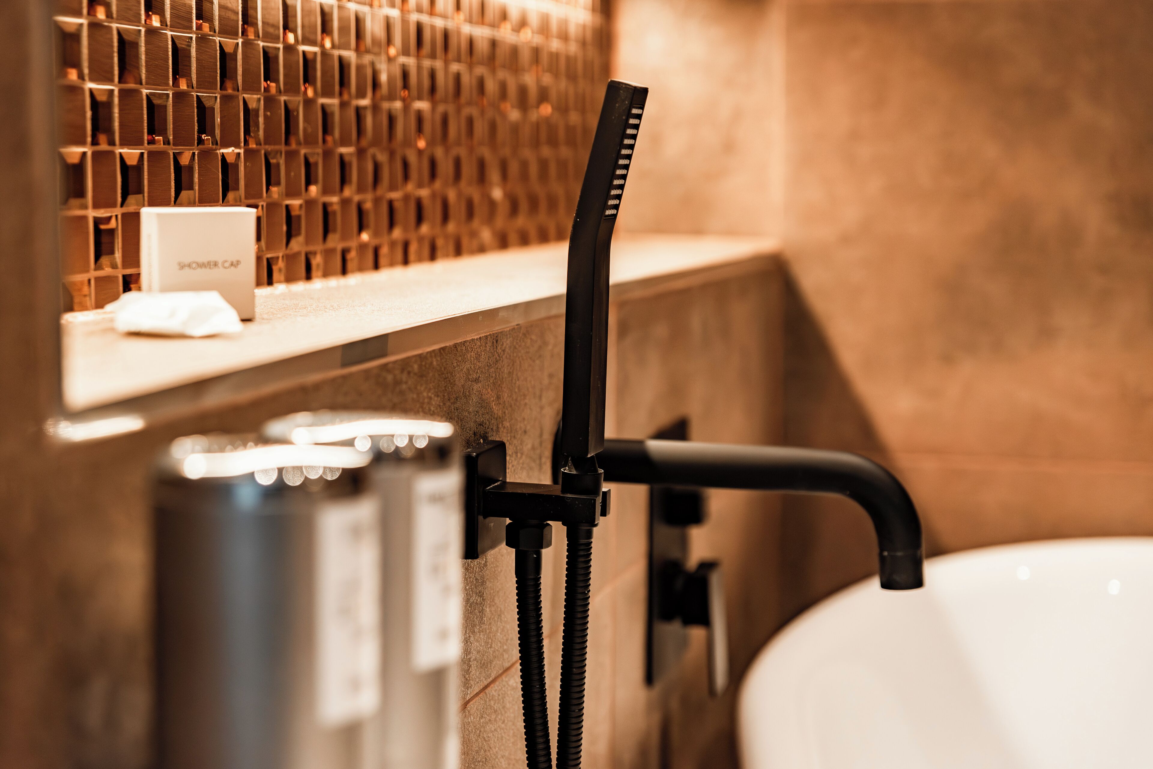 A shower area with a modern faucet and a shower cap on the counter.