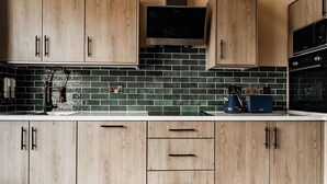 Eine Küche mit Holzschränken, einer schwarzen Fliesenrückwand und modernen Geräten.