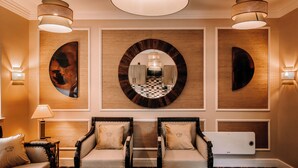 Eine moderne Hotellobby mit zwei Sesseln, einem Sofa, einem Schachbrettmuster-Boden und einem großen Wandspiegel.