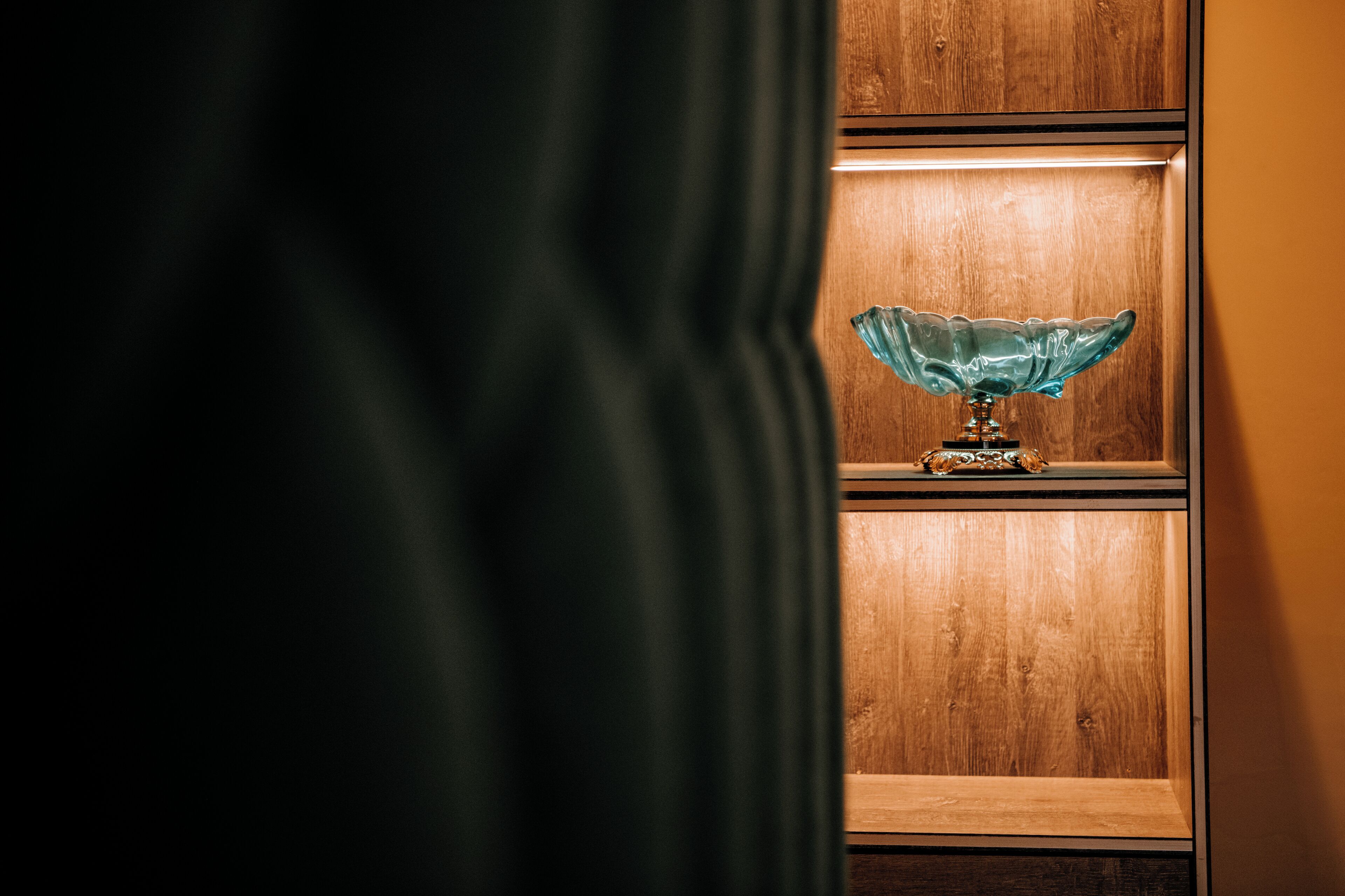 A wooden shelf with a glass bowl lamp.