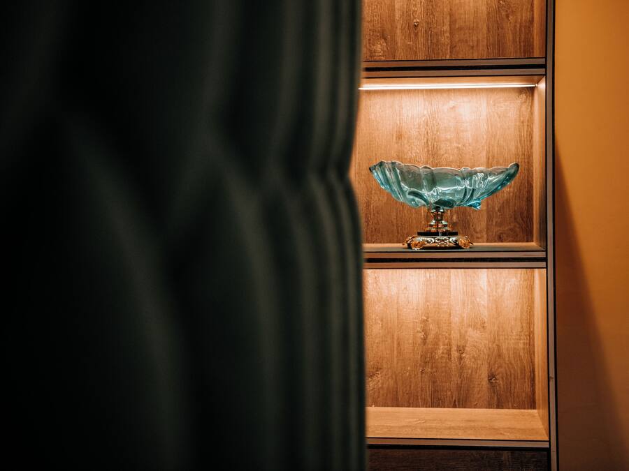 A wooden shelf with a glass bowl lamp.