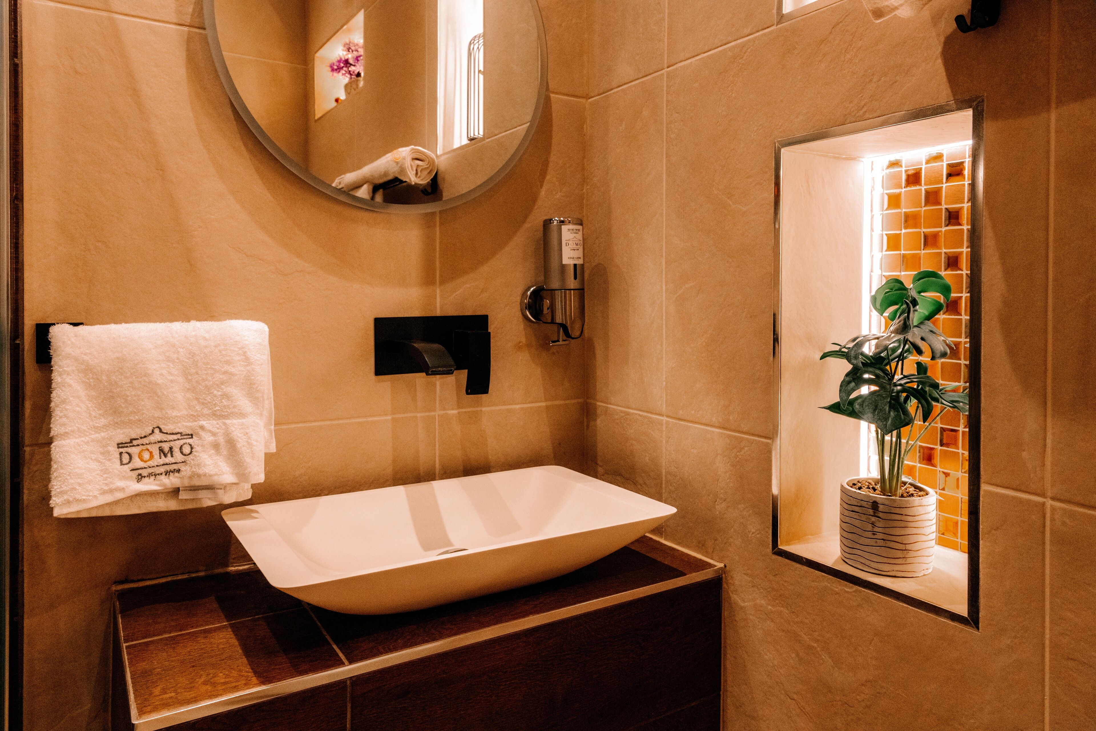 A bathroom with a white sink, a towel hanging on the wall, and a potted plant in a window.