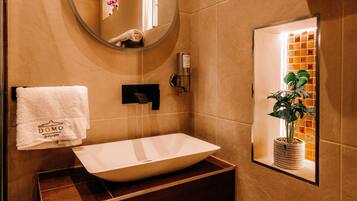 A bathroom with a white sink, a towel hanging on the wall, and a potted plant in a window.
