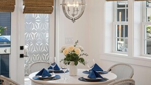 Un espace repas avec des tables rondes, des serviettes bleues, des assiettes blanches et un vase rempli de fleurs blanches.