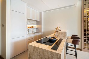 Une cuisine moderne dotée d’un îlot central, de meubles blancs et d’un coin bar avec des tabourets.