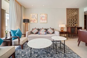 A modern living room with a sofa, two round tables, a coffee table, and a patterned rug.