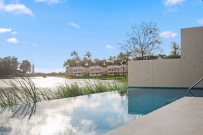 Une piscine offrant une vue dégagée sur un complexe hôtelier situé en bord de mer, en arrière-plan.
