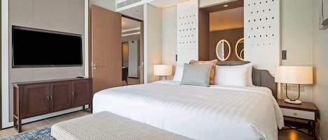 Ein modernes Hotelzimmer mit einem großen Bett, einem Flachbildfernseher, einer Holzkommode und einer dekorativen Wandverkleidung.
