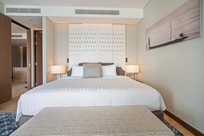 A hotel room with a large bed, two bedside lamps, a decorative panel, and a painting on the wall.
