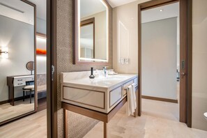 A modern bathroom with a large mirror, a marble sink, and a wooden vanity.