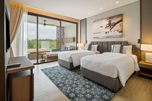 Ein Hotelzimmer mit zwei Betten, einem Schreibtisch, einem Balkon mit Tisch und Stühlen sowie einem Bild an der Wand.