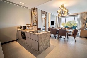Cocina moderna con una isla de mármol, comedor con sillas y un ventanal con vistas.