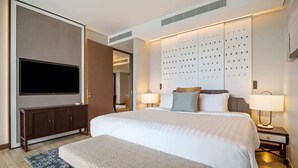 A modern hotel room with a large bed, a flat-screen TV mounted on the wall, a wooden cabinet, two bedside lamps, and a patterned rug. - Angsana Oceanview Residences, Two-Bedroom 162 C Penthouse (Choeng Thale)