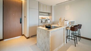 A modern kitchen with a marble island, bar stools, and built-in cabinets. - Angsana Oceanview Residences, Two-Bedroom 162 C Penthouse (Choeng Thale)