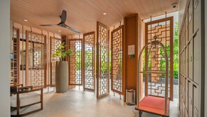 A hotel lobby with traditional wooden partitions, a ceiling fan, a reception desk, and a red trolley. - Angsana Oceanview Residences, Two-Bedroom 162 C Penthouse (Choeng Thale)