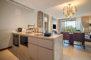 A modern kitchen with built-in appliances, a dining area with a table and chairs, and a living room with a sofa and a TV.