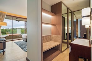Une chambre d’hôtel moderne dotée d’un balcon, d’un bureau, d’un canapé, d’un miroir et d’une armoire en bois.