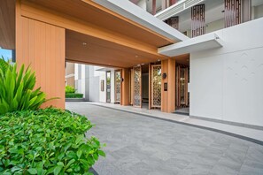 A modern hotel entrance with a covered walkway, wooden columns, and traditional decorative screens.