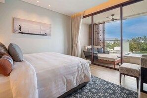 A hotel room with a large bed, a balcony with a sofa, and a painting on the wall.