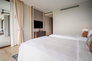 A modern hotel room with a large bed, a flat-screen TV, a wardrobe, and a bathroom visible through an open door. - Angsana Oceanview Residences, Two-Bedroom 164 Cc Penthouse (Choeng Thale)
