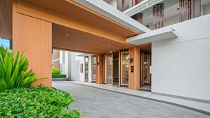 A modern hotel entrance with a covered walkway, wooden columns, and traditional decorative screens.