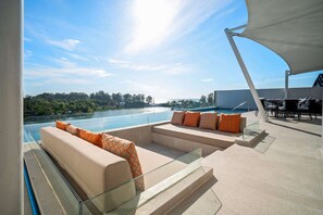 A rooftop terrace with a pool, outdoor seating, and a view of the landscape.