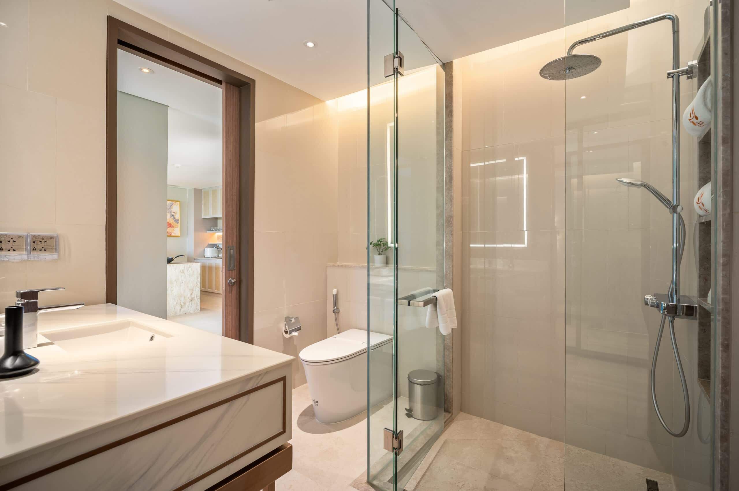 A modern bathroom with a glass-enclosed shower, a white sink, and a toilet.