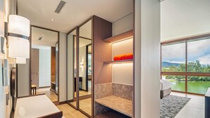 A modern hotel room with a large window, a built-in bench, and a desk with a lamp.