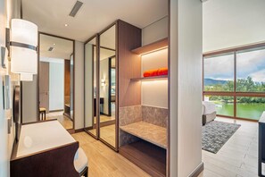 Habitación de hotel moderna con un ventanal grande, una banca integrada y un escritorio con lámpara.