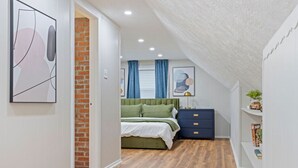 A bedroom with a green bed, a blue dresser, and a brick wall. - Soak and Play: Hot Tub + Family Arcade Fun (Euclid)