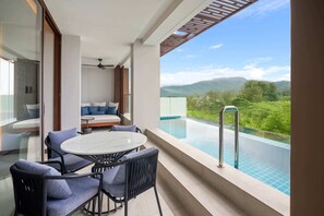 Un balcón con piscina, un sofá y una mesa con sillas.