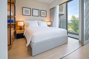 Ein modernes Hotelzimmer mit einem großen Bett, einem Nachttisch, einem Kleiderschrank und einem großen Fenster mit Blick ins Freie.