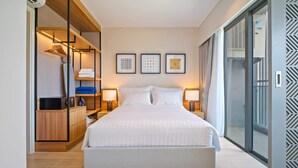 A modern hotel room with a large bed, bedside lamps, a wardrobe, and a view through a glass door.