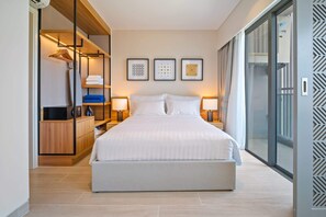 Une chambre d’hôtel moderne avec un grand lit, des lampes de chevet, une armoire et une vue sur l’extérieur grâce à une porte vitrée.
