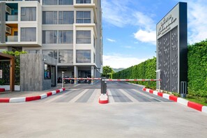 Une entrée fermée par un portail mène à un immeuble moderne sur lequel on peut lire l’inscription « Laguna Residences ».