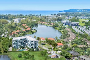 A coastal resort with a central lake, surrounded by lush greenery and residential buildings. - Laguna Lakeside, One Bedroom A2 Deluxe (Choeng Thale)