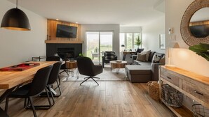 A modern living room with a fireplace, a dining area with a wooden table, and a sofa set. - 2-Level Home • Tremblant Mountain View • Fireplace (Mont-Tremblant)