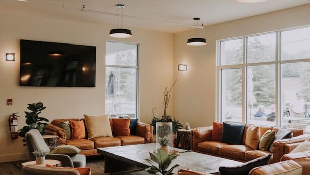 A spacious living room with leather sofas, a coffee table, and a TV mounted on the wall. - 2-Level Home • Tremblant Mountain View • Fireplace (Mont-Tremblant)