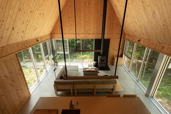 A wooden cabin interior with a sofa, dining table, and a fireplace.