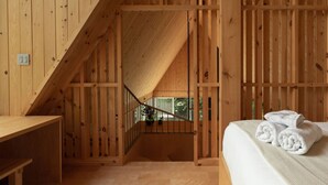Un interior de madera con una escalera que lleva a un balcón.