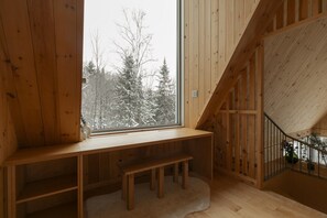 Un intérieur en bois avec une grande fenêtre, un banc et un escalier.
