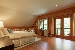Ein Schlafzimmer mit Bett, Schreibtisch und Stuhl, Holzwänden und einem großen Fenster.