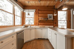 A kitchen with white cabinets, a built-in dishwasher, and a wooden ceiling.