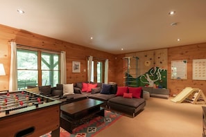 A cozy living room with a foosball table, a sofa set, a climbing wall, and a slide.