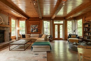 A log cabin interior with a fireplace, a sofa, a coffee table, and a bookshelf.