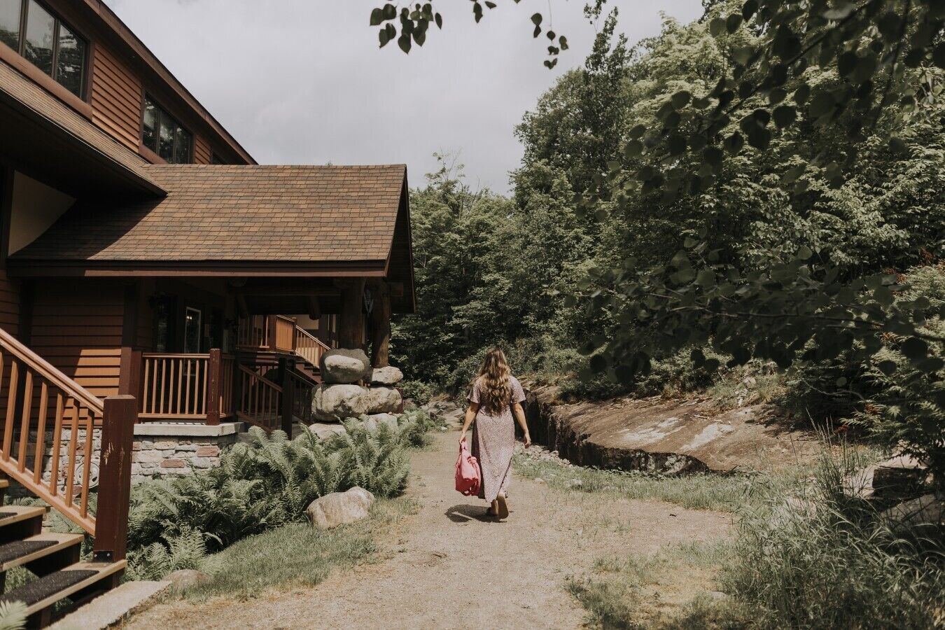A wooden cabin with a porch, stone steps, and a natural surrounding.